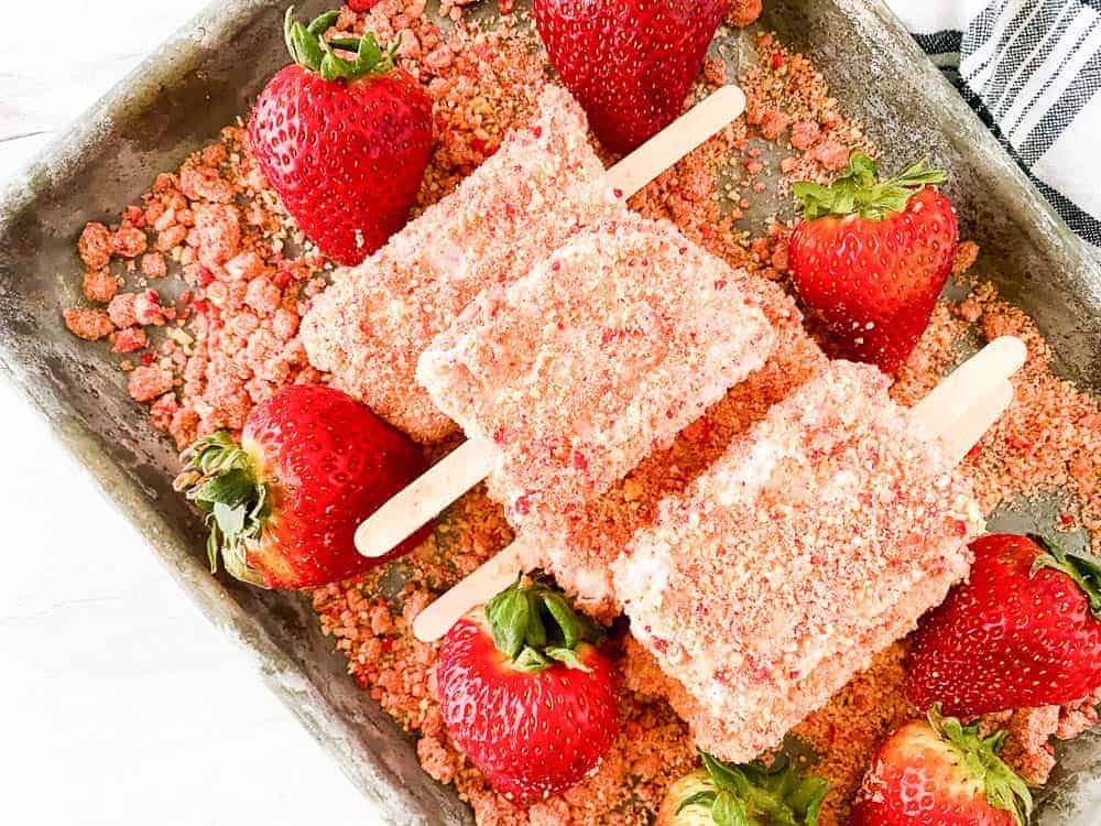 Strawberry crunch bars on a tray with strawberries around it.