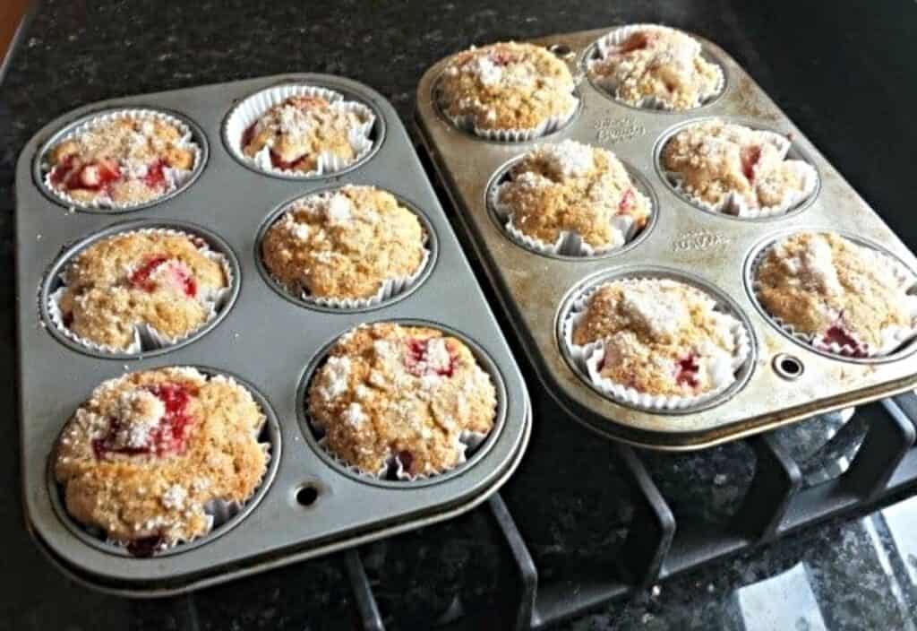 Two pans of strawberry muffins sitting on a black stovetop.