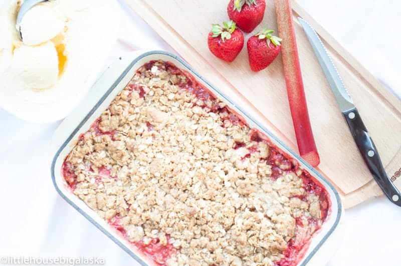 Strawberry Rhubarb Bars in a 9x13 pan with strawberries and rhubarb.