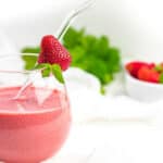 Strawberry Mint Keto Smoothie inside a glass with straw and fresh strawberry.