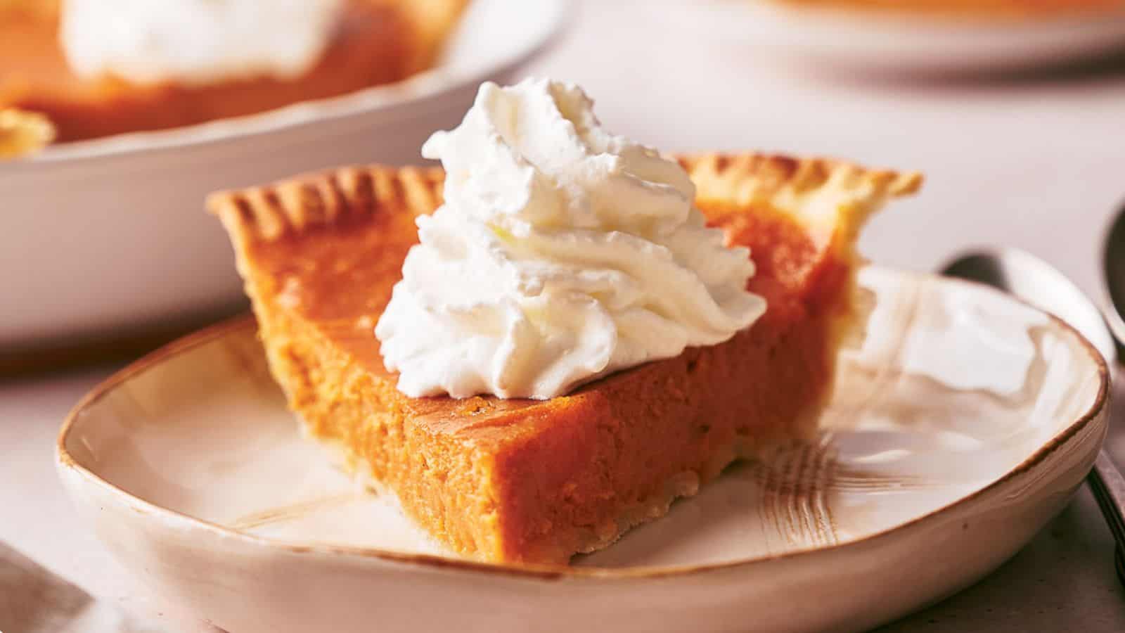 A slice of sweet potato pie with a swirl of cream on it.