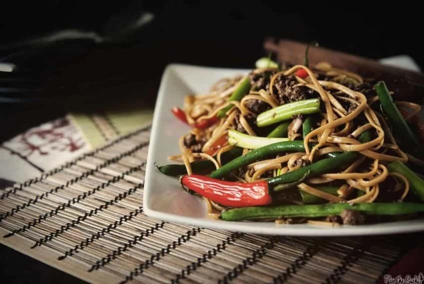 Szechuan Beef and Noodles on white plate with green beans