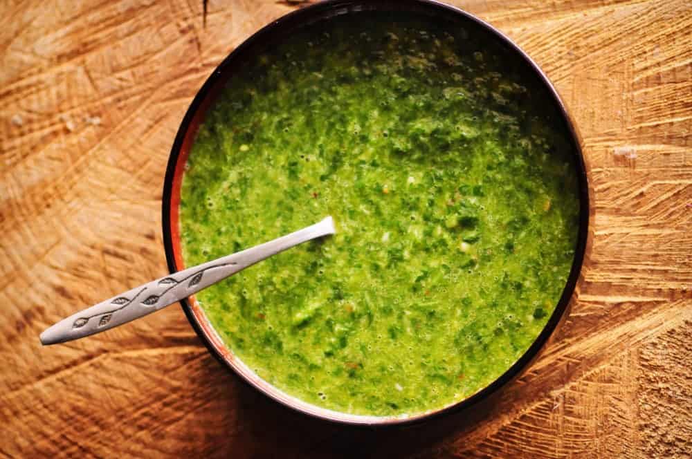 A small black bowl filled with a vibrant green sauce.
