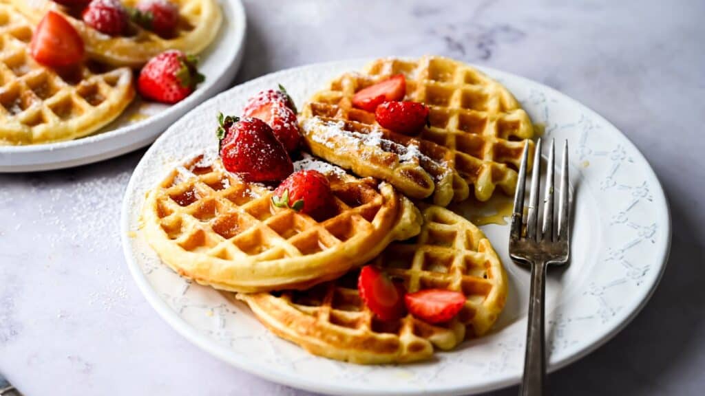 Freshly made waffles on a plate with strawberries.