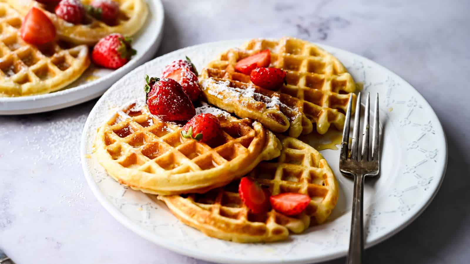 Freshly made waffles on a plate with strawberries.