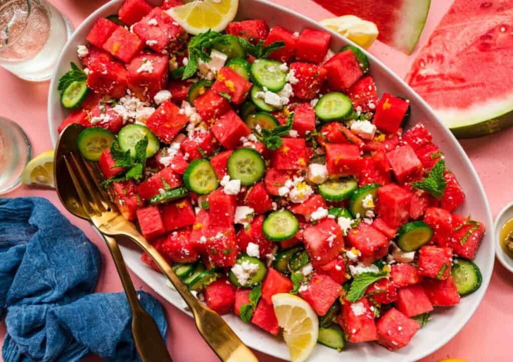 Overhead view of a watermelon feta cucumber salad on a large platter.
