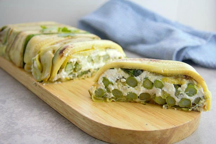 Terrine of zucchini strips with a cheese and asparagus filling on a board.