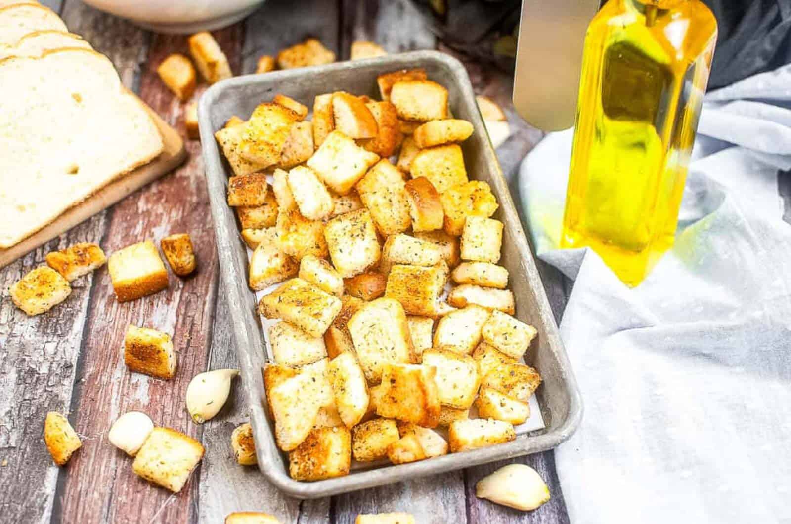 Low angle shot of croutons on a small metal baking sheet.