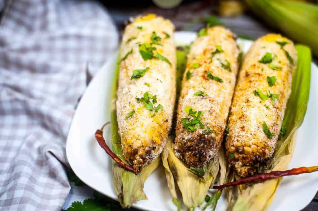 Corn elote on a white plate.