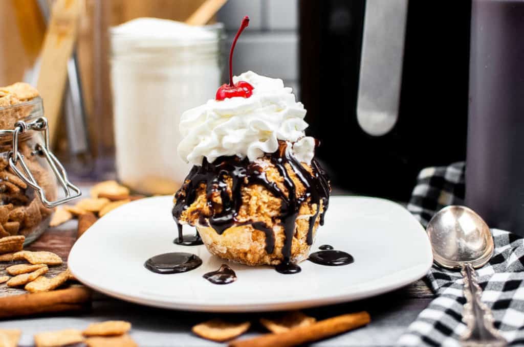 Fried ice cream scoop topped with whipped cream and chocolate sauce.