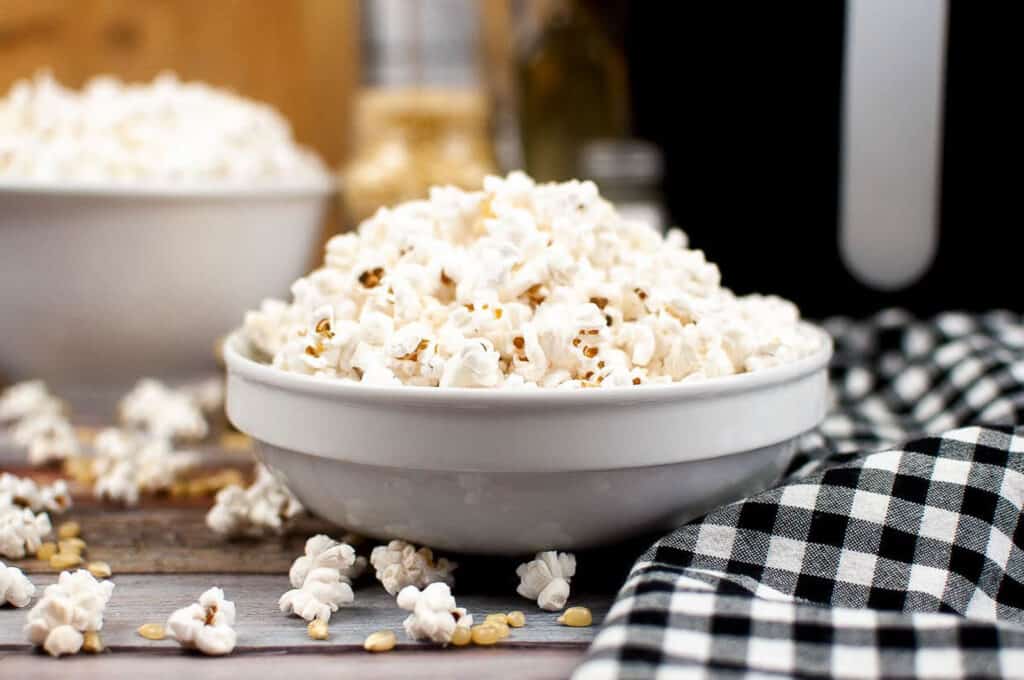 Popcorn in a white bowl with a black and white checked napkin.