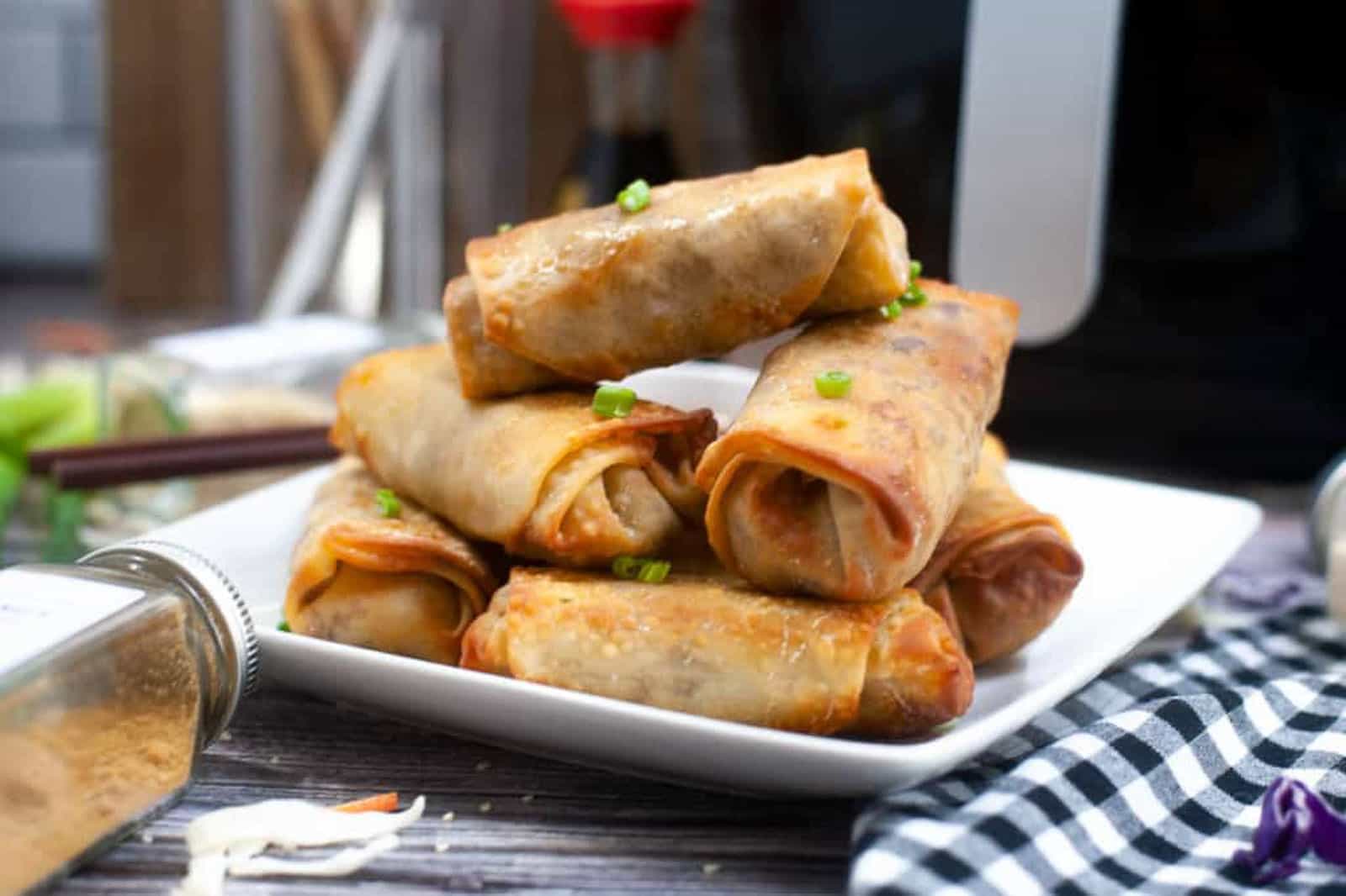 Stacked spring rolls on a white plate.