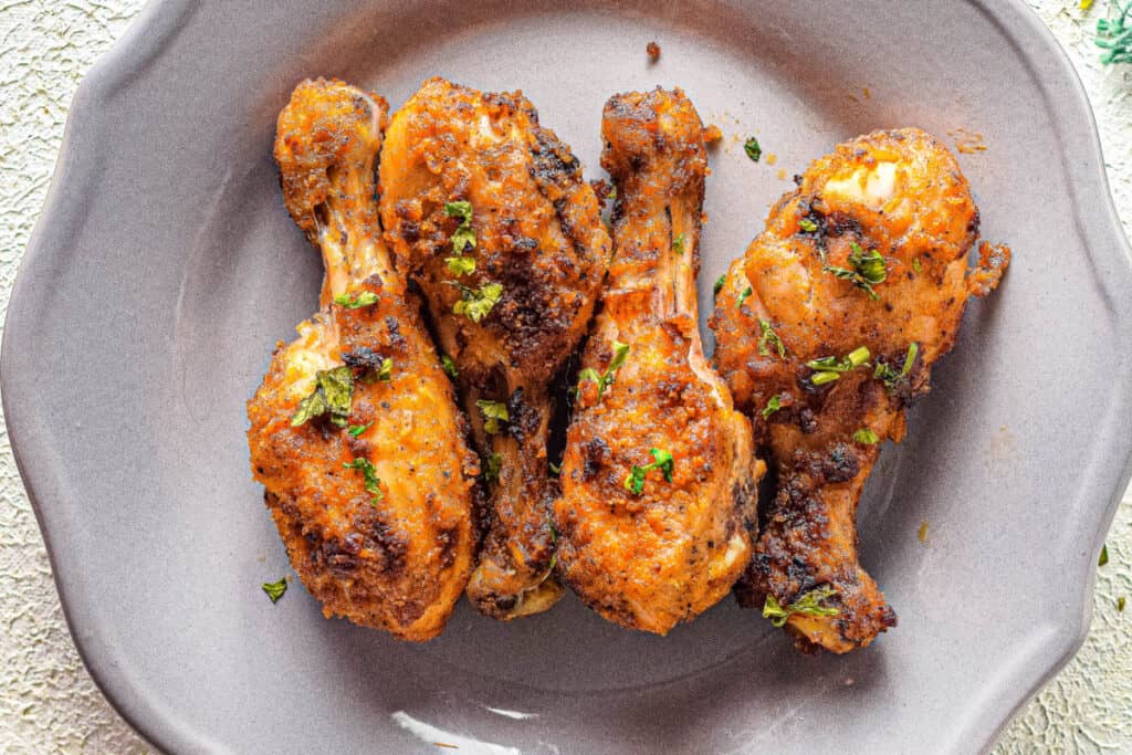Crispy chicken drumsticks on a plate with parsley.