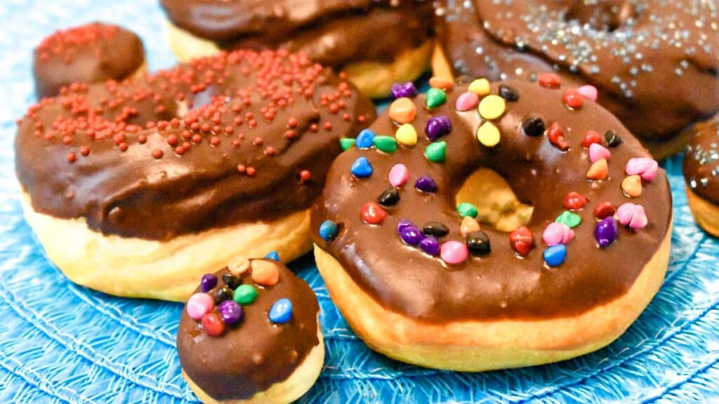 Biscuit donuts decorated with chocolate frosting and sprinkles on a napkin.