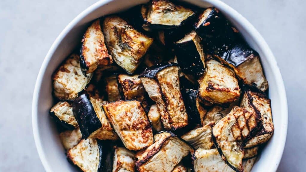A white bowl filled with cubed eggplant.