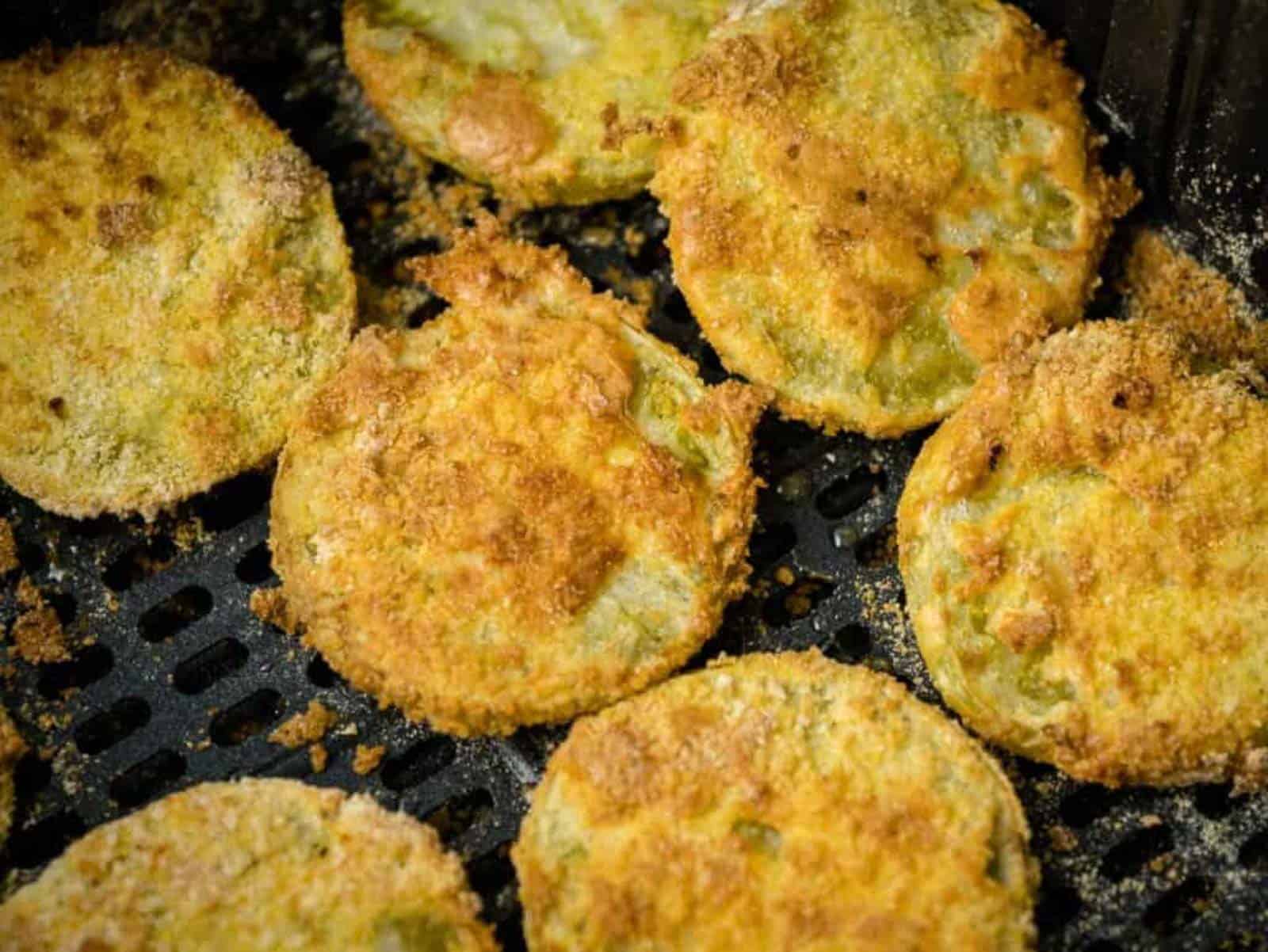 Fried green tomatoes in an air fryer basket.