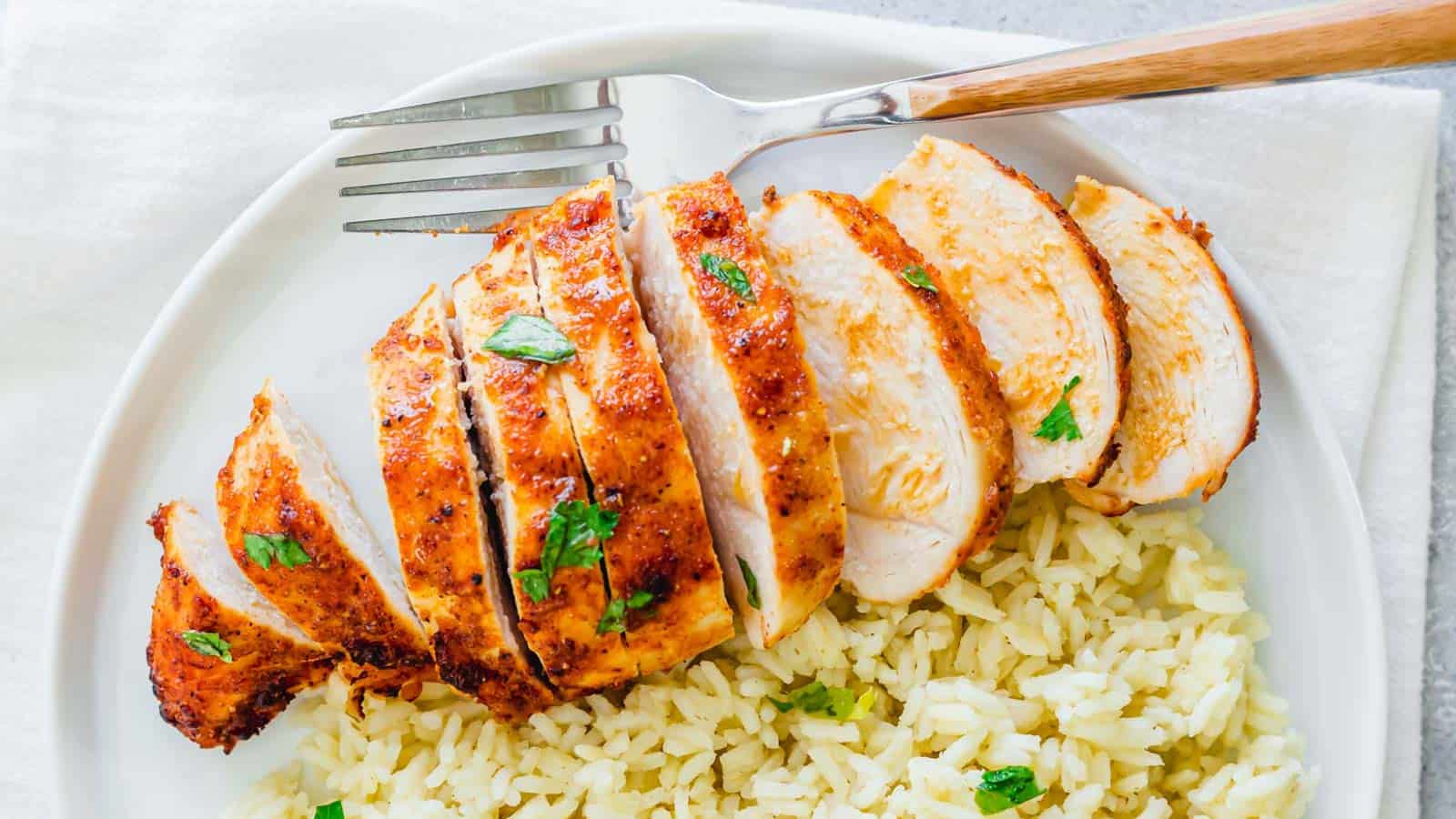 Air fryer frozen chicken breast sliced on a plate with rice and a fork.