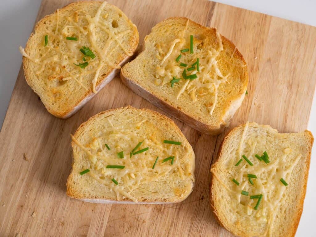 Top view of garlic bread with butter, garlic, Parmesan cheese and chives.