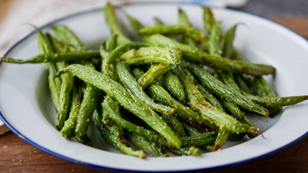 closeup of air fryer green beans on a plate with a blue rim.