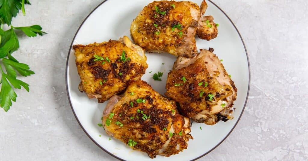 Air Fryer Keto Chicken Thighs on a white plate topped with parsley.