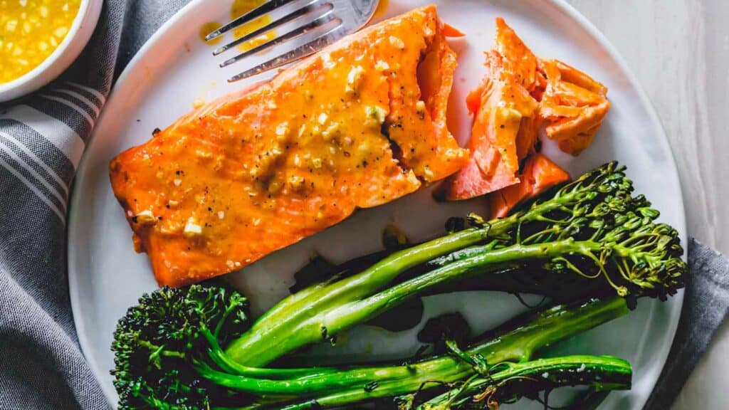 Maple mustard air fryer frozen salmon filet with broccolini on a plate.