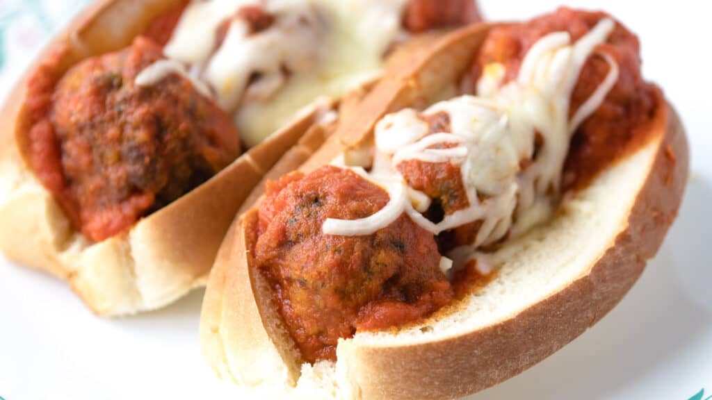 meatball subs in a bun topped with melted cheese.