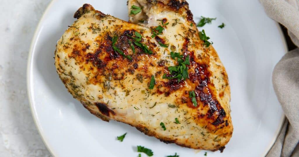 air fryer ranch chicken breast on a white plate topped with parsley