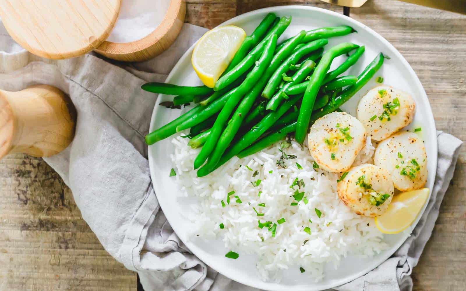 Air fryer scallops with green beans and rice on a plate.