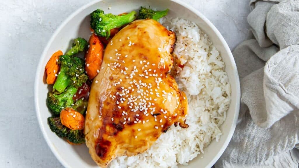 air fryer teriyaki chicken breast in a white bowl with rice and vegetables.