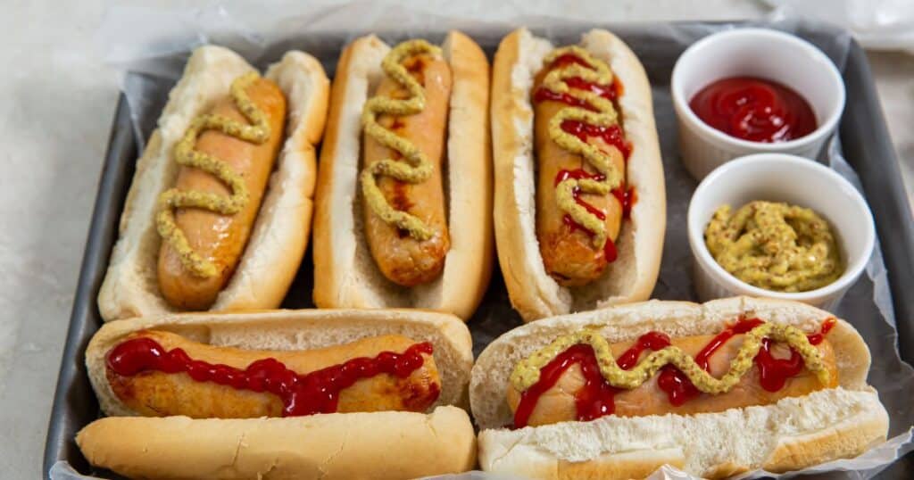 Trader Joe's Chicken Sausage in buns with toppings in a tray.