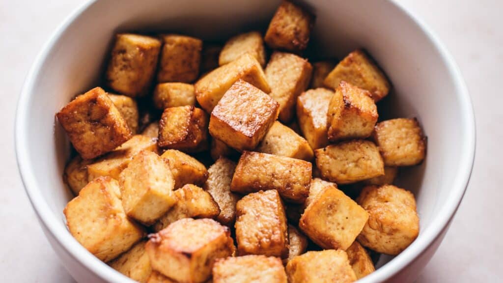 A white ceramic bowl filled with cubed cooked tofu.