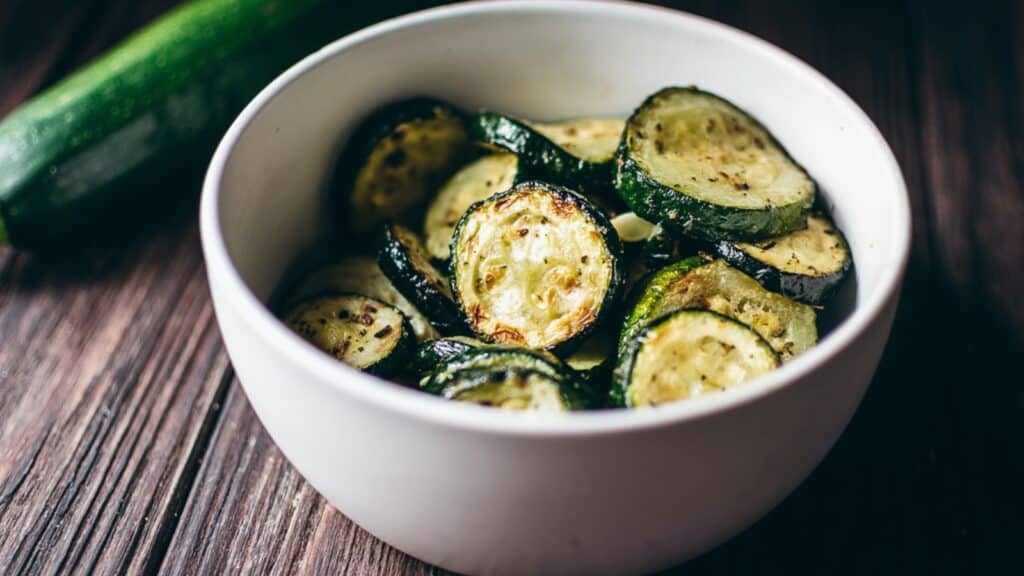 A white bowl filled with sliced green zucchini.
