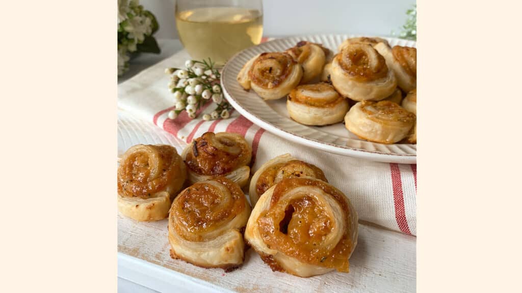 Baked apricot pinwheel appetizers on a white plate and a white board.