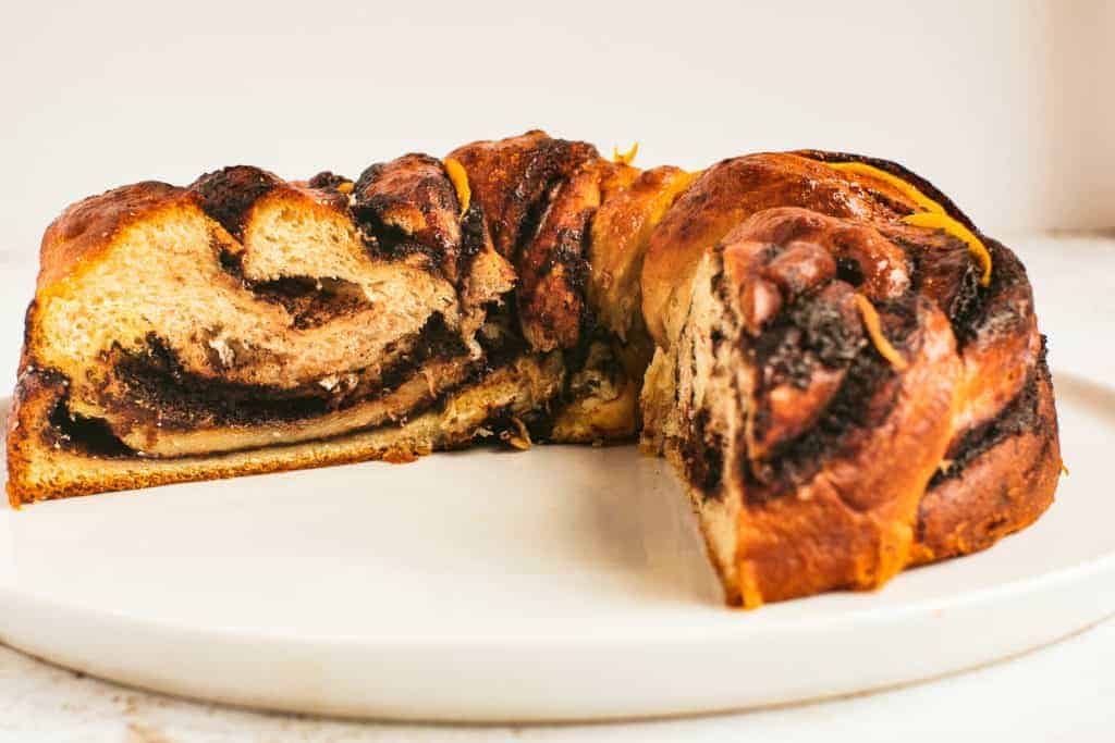 low angle shot of a chocolate babka with a wedge removed so you can see the inside.