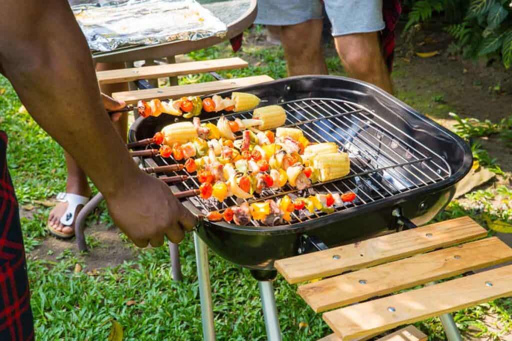 Man cooking kabobs on an outdoor grill.