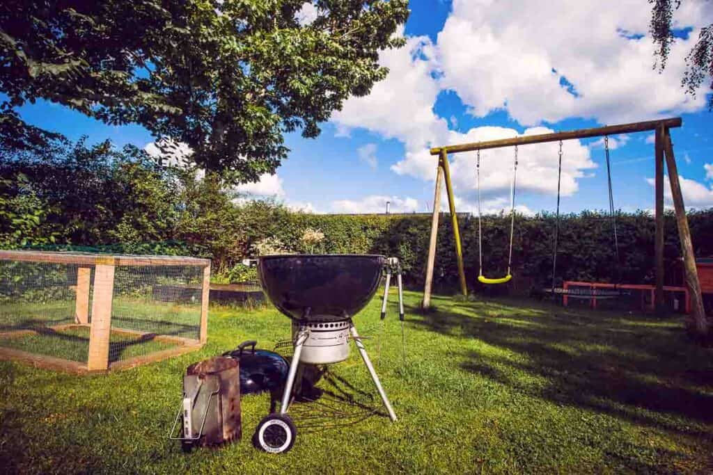 A backyard with a BBQ and swing set.