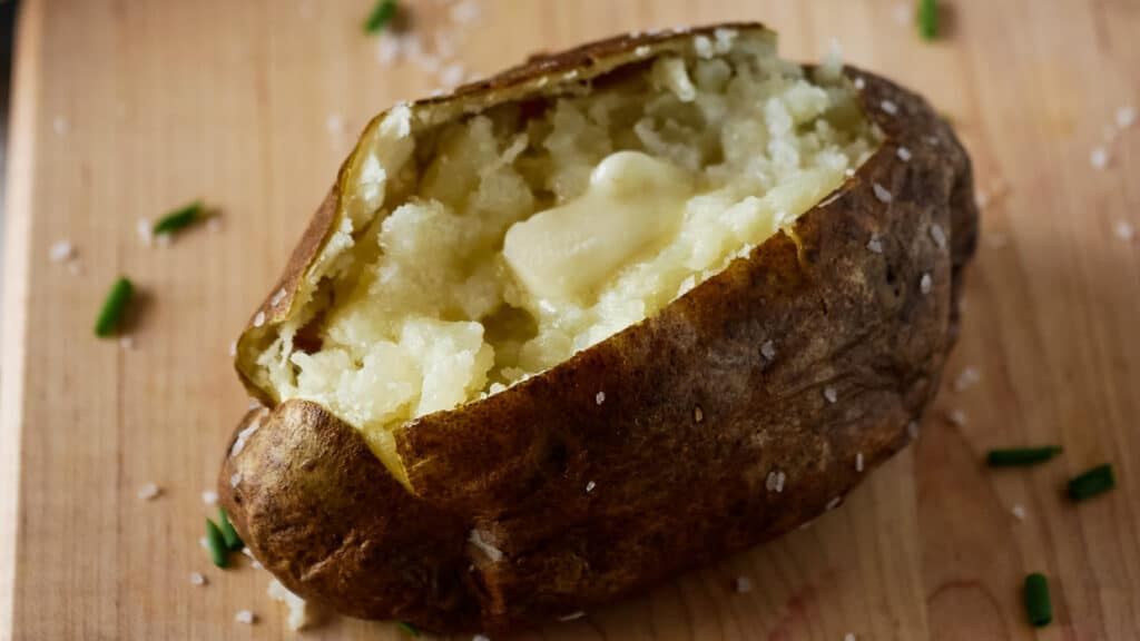 Closeup of an air fryer baked potato topped with butter that is melting.