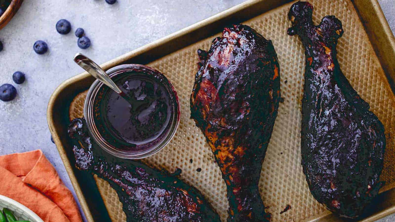 Blueberry BBQ turkey legs on a baking sheet.