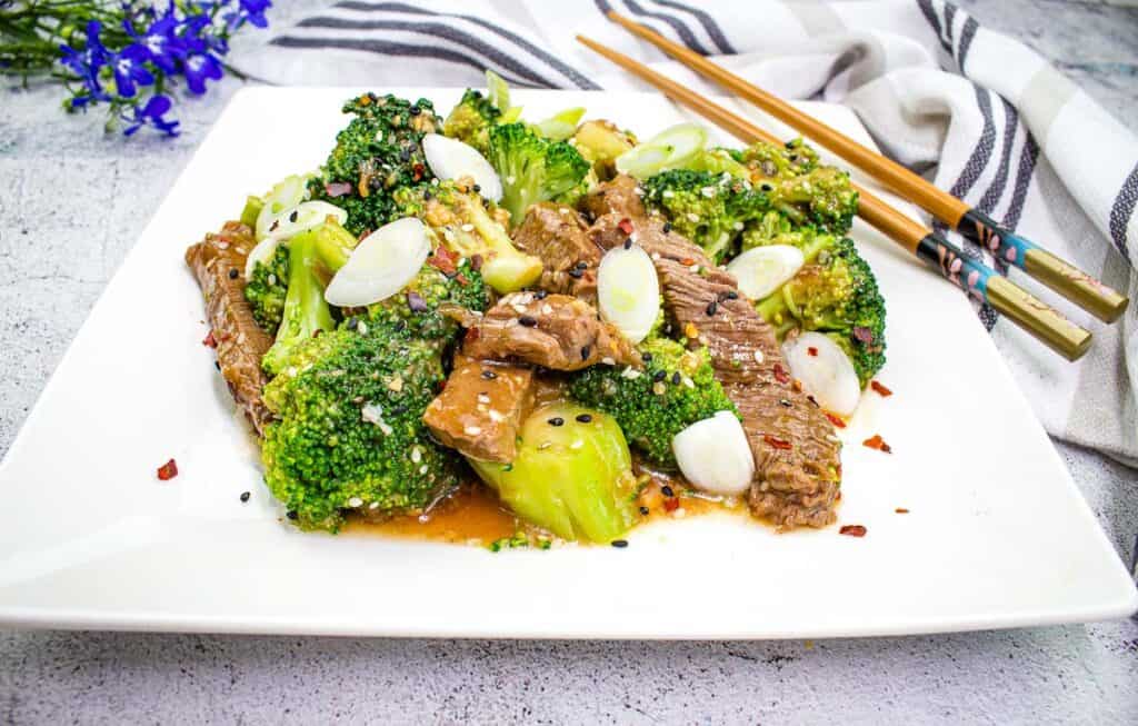 Low-carb Beef and Broccoli on a square plate with chopsticks.