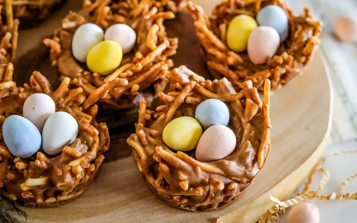 No bake birds nest cookies filled with chocolate eggs on a cutting board.