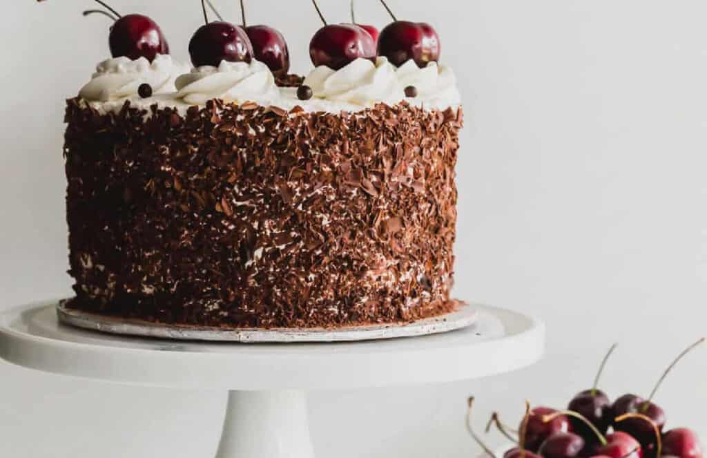 A black forest cake on a white stand.