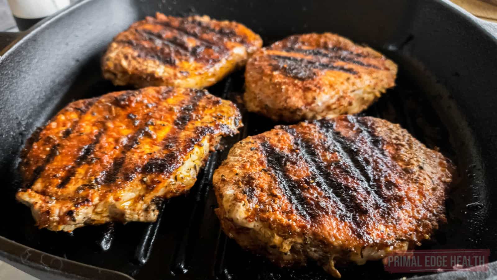 Four blackened pork chops recipe in cast iron grill pan.