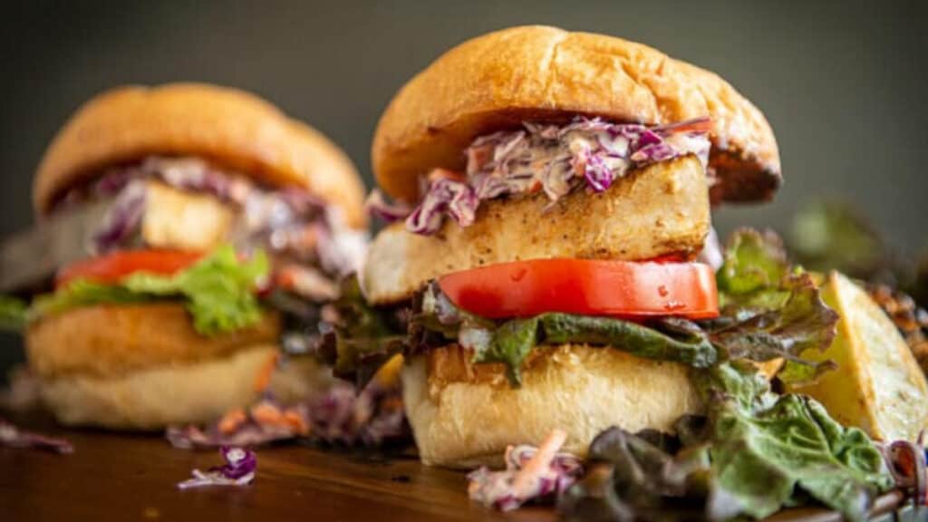 blackened swordfish sandwiches with tomatoes, lettuce and coleslaw.