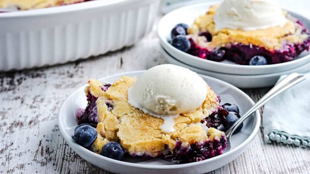 Two plates of blueberry cobbler topped with vanilla ice cream.