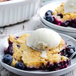 Two plates of blueberry cobbler topped with vanilla ice cream.