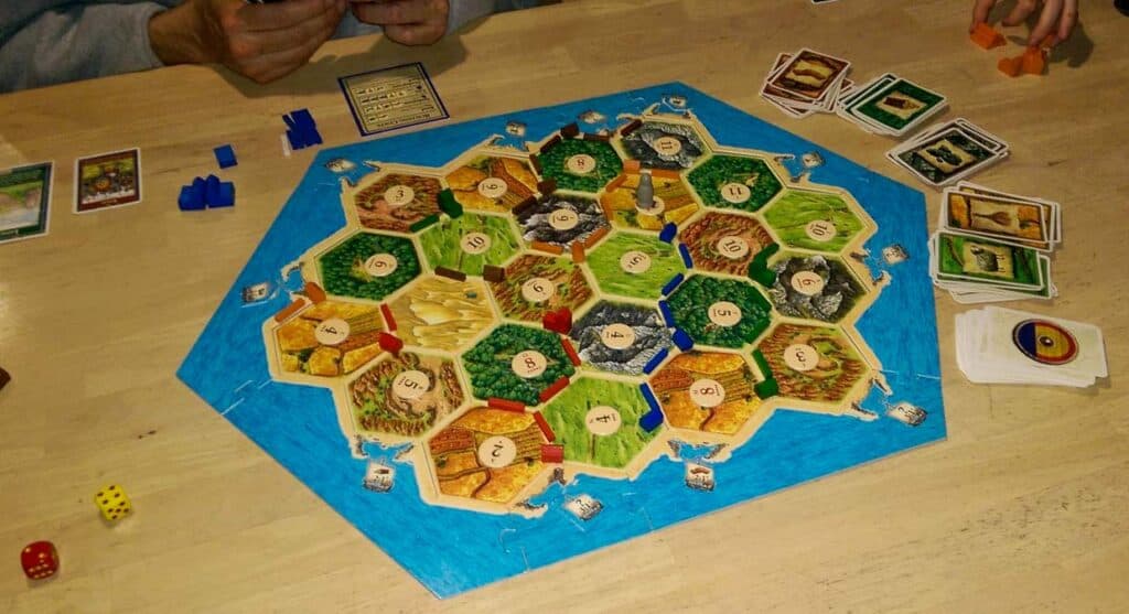 Settlers of Catan game setup with cards and pieces on the board.