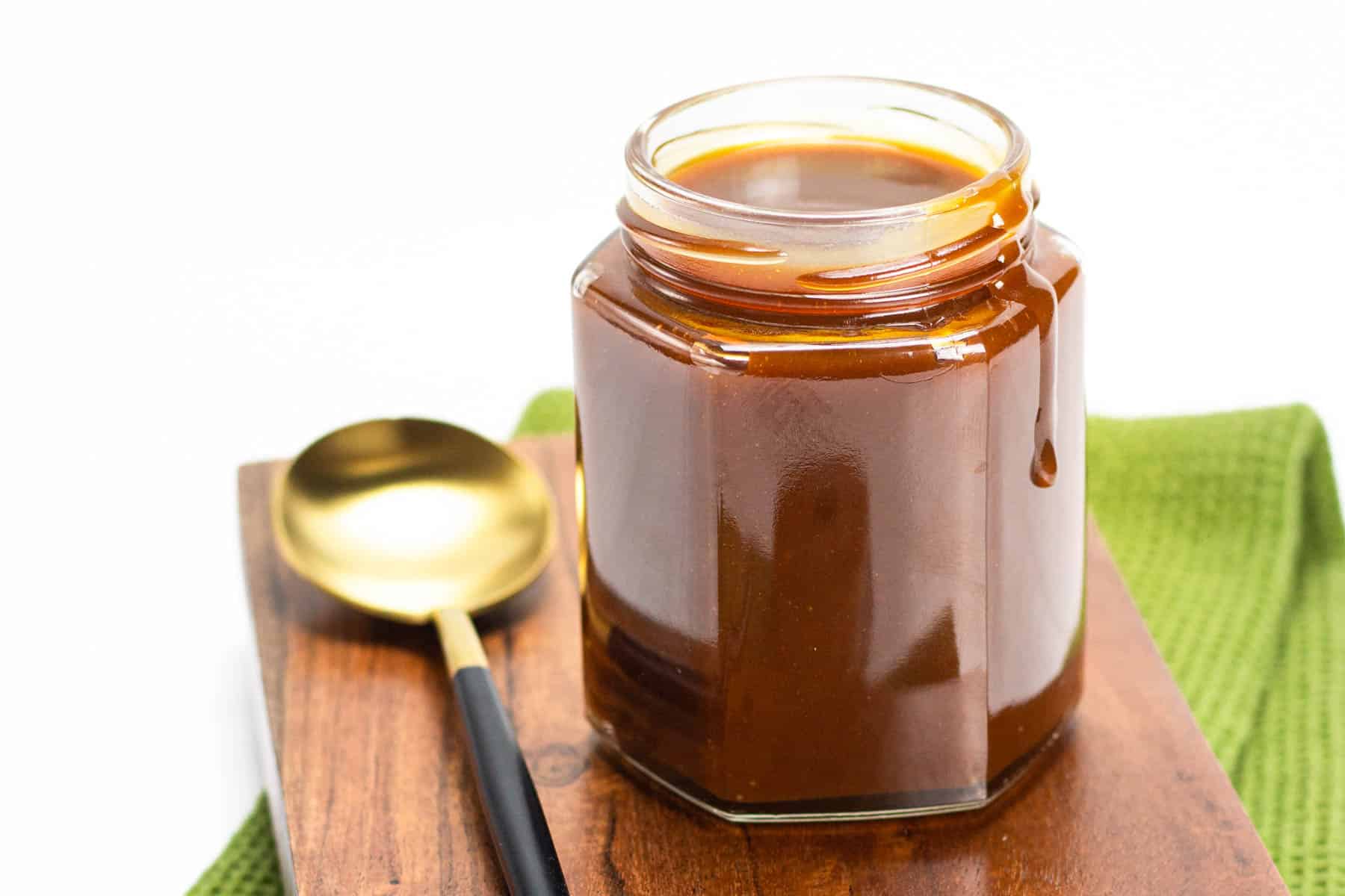 bourbon caramel sauce on a wood board with a gold spoon.