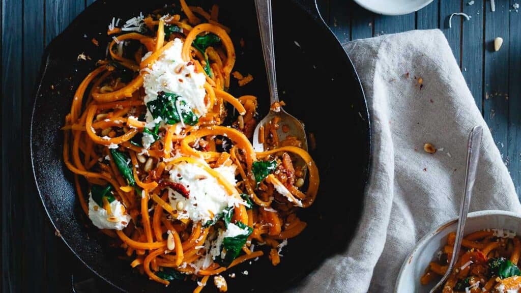 Butternut squash noodles with spinach, ricotta and garlic in a cast iron skillet.