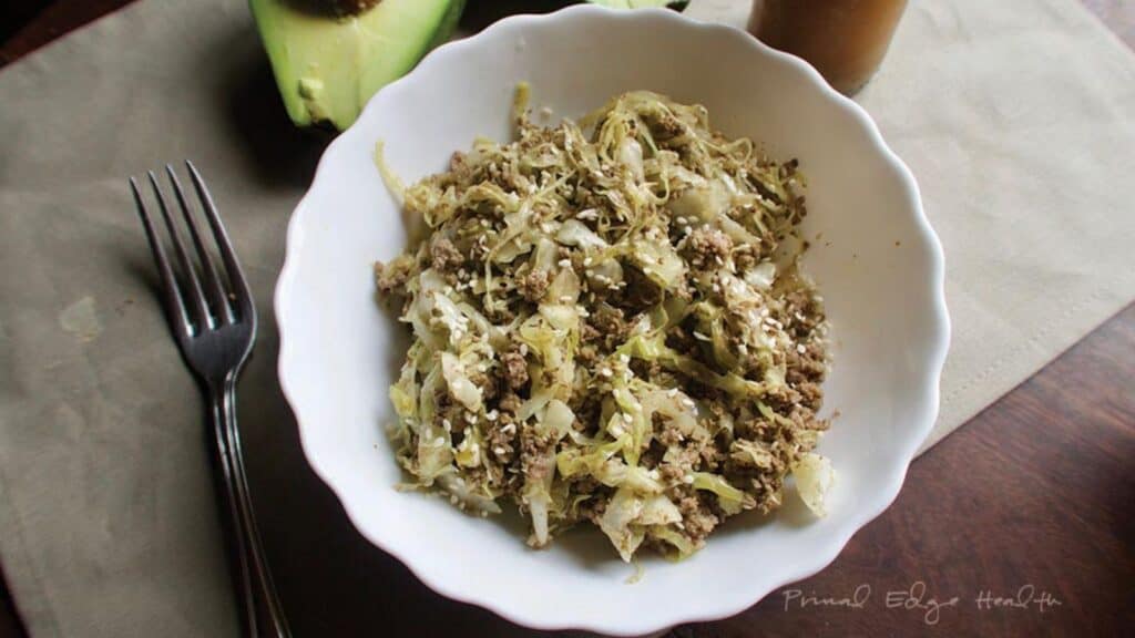 Cabbage Noodles with Ground Beef in white bowl with avocado