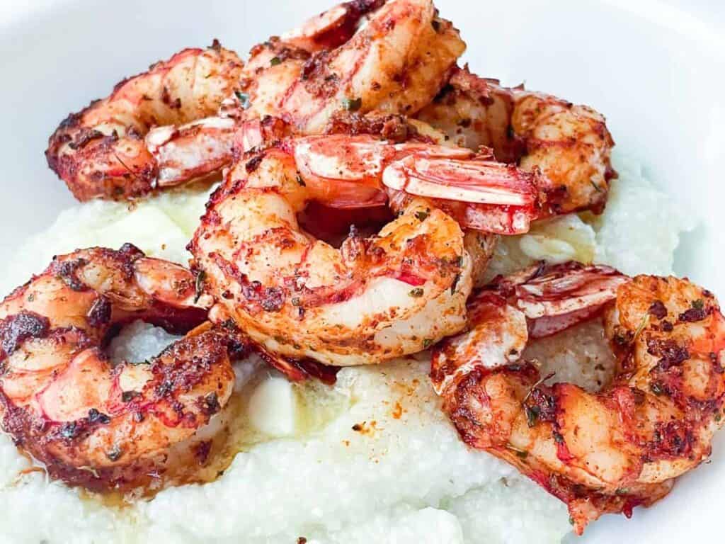 Zesty cajun shrimp on fresh grits with butter melting under them.